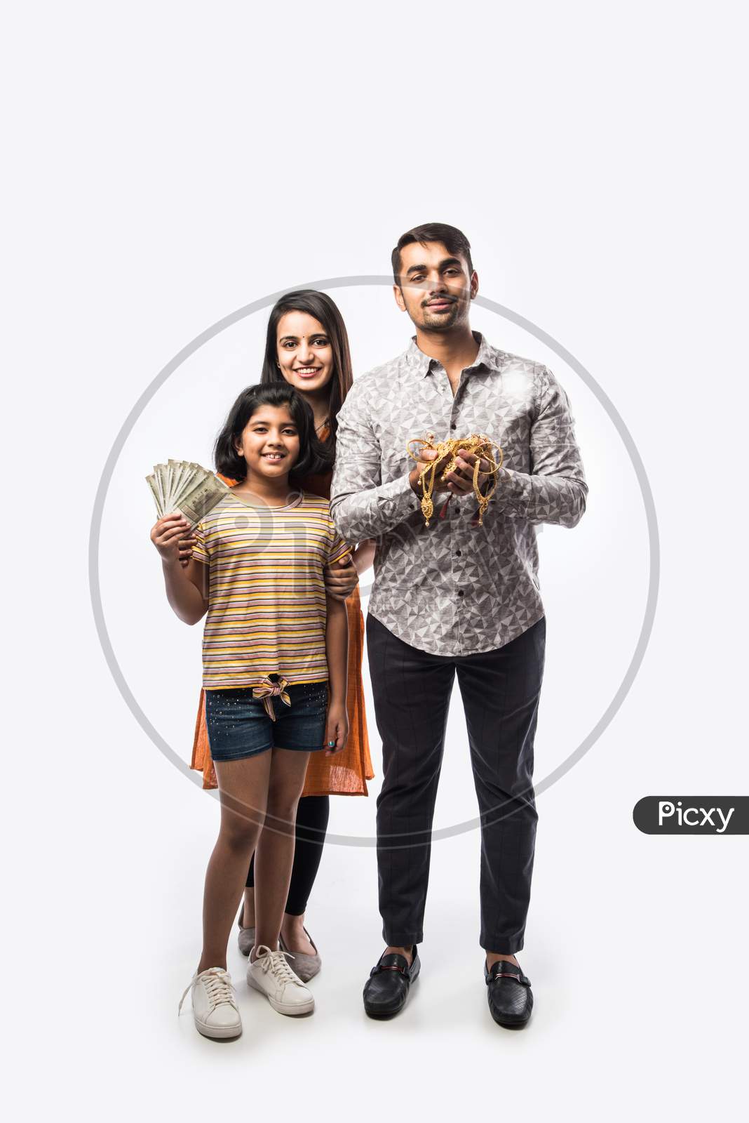 Indian couple with cute daughter holding gold jewelry, ornaments - Asset or Gold Loan concept