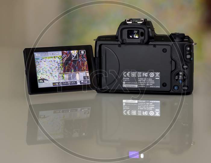 Frankfurt, Germany - 26th August 2020: A german photographer takes pictures of his old Canon EOS M50 with the KIT lens and additional equipment in order to sell it, showing the back with display.