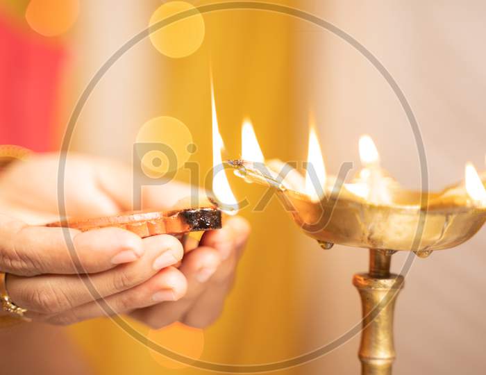 Closeup Of Woman Hands Lighting Lantern Diya Or Lamp During Festival Ceremony - Concept Of Traditional Indian Festival And Ritual Celebrations.