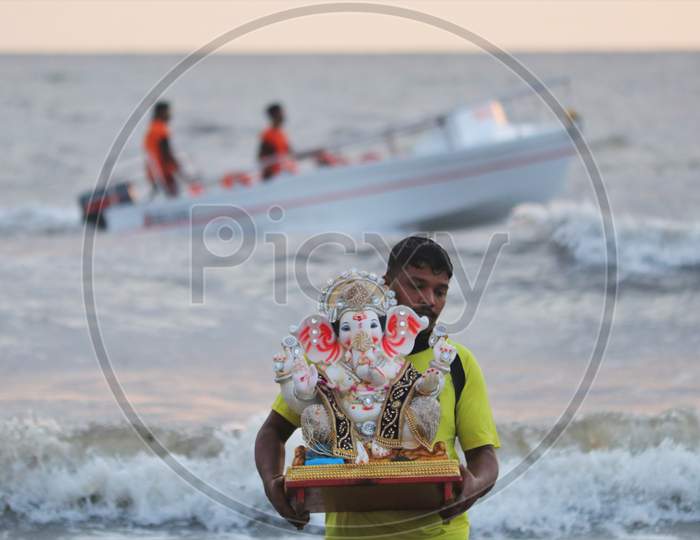 A man carries an idol of the Hindu god Ganesh, the deity of prosperity, to immerse it into the waters of the Arabian sea on the fifth day of the 10-day long Ganesh Chaturthi festival in Mumbai, India on August 26, 2020.