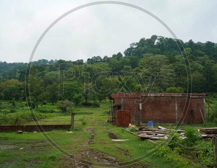 A House Being Constructed With Red Bricks In Between Mountain Range.
