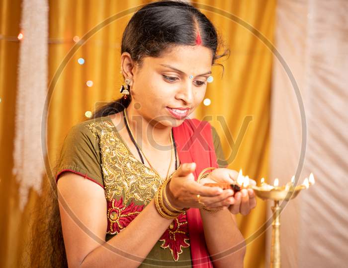 Happy Smiling Indian Woman Lighting Lantern Or Diya Lamp During Festival Ceremony At Home - Concept Of Traditional Festival And Ritual Celebrations.