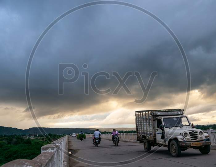 Vehicles passing over a bridge under the cloudy sky