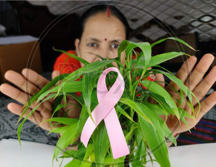 Woman Behind Pink ribbon a cancer survivor, Selective focus on ribbon