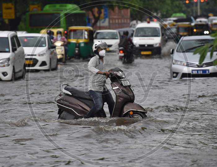 Commuters drive along a waterlogged road during heavy rain at Baba Kharak Singh Marg in New Delhi on August 28, 2020.