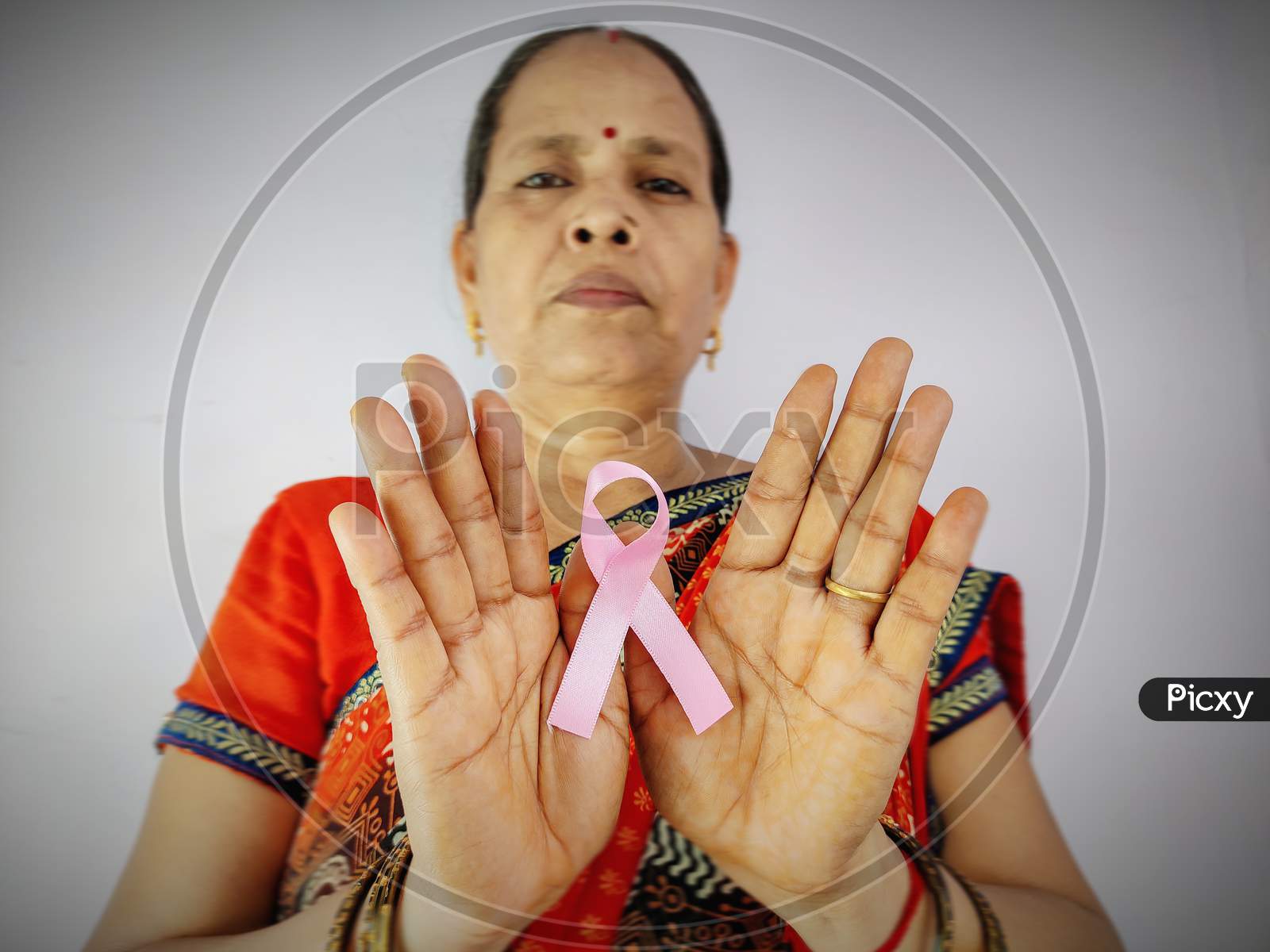 Indian woman Hand holding pink ribbon , Breast cancer awareness symbol, fight against cancer