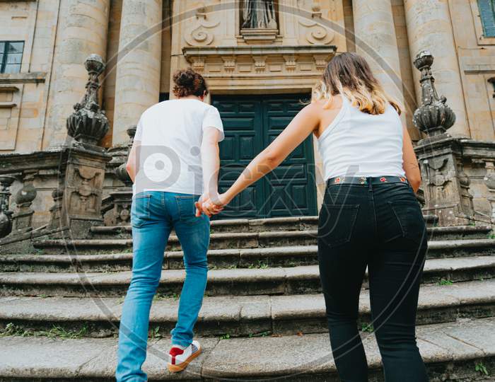 Young Couple Going Up Stairs While Grabbing Hands In An Ancient Building