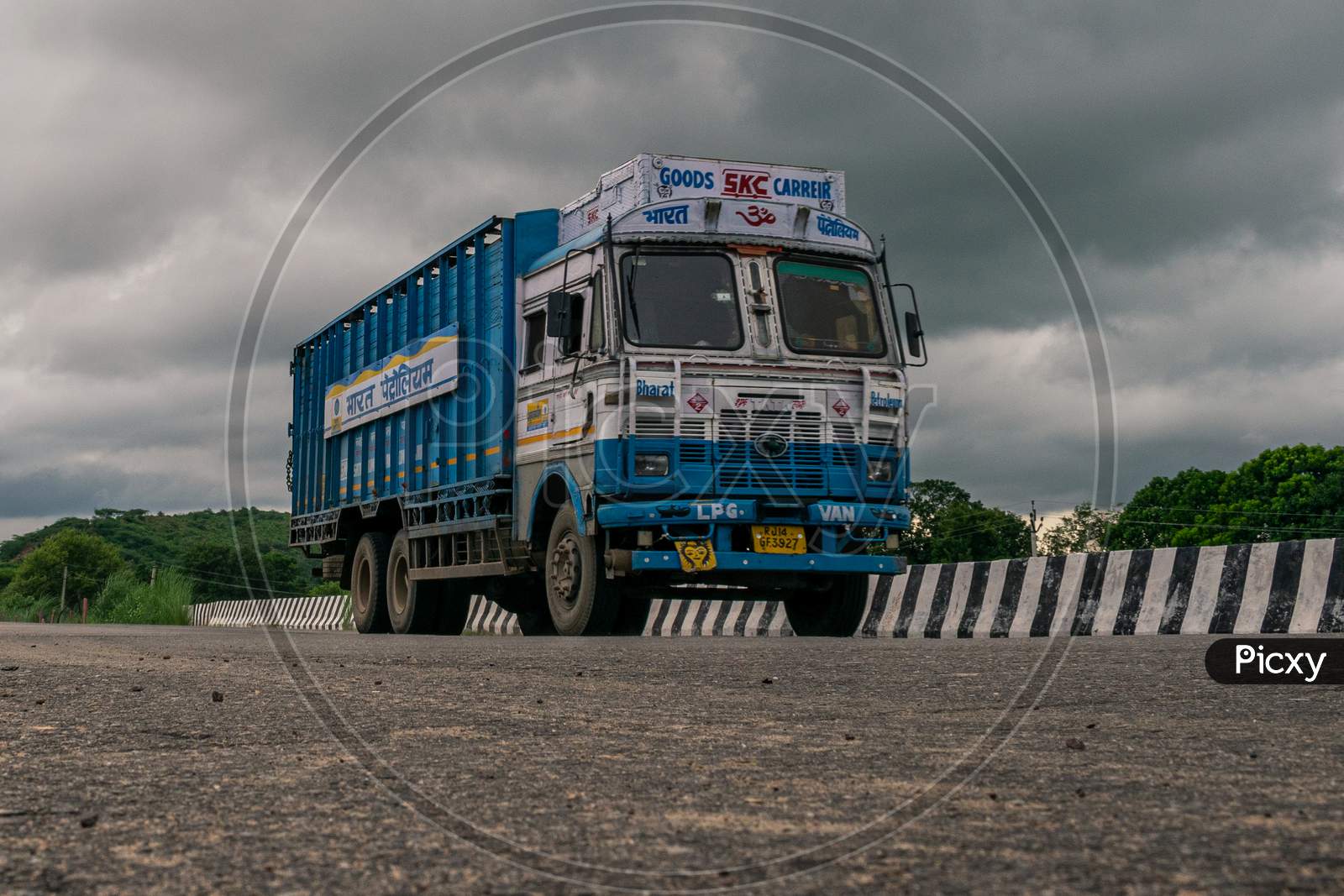 A Bharat Petroleum truck passing over a bridge under cloudy sky