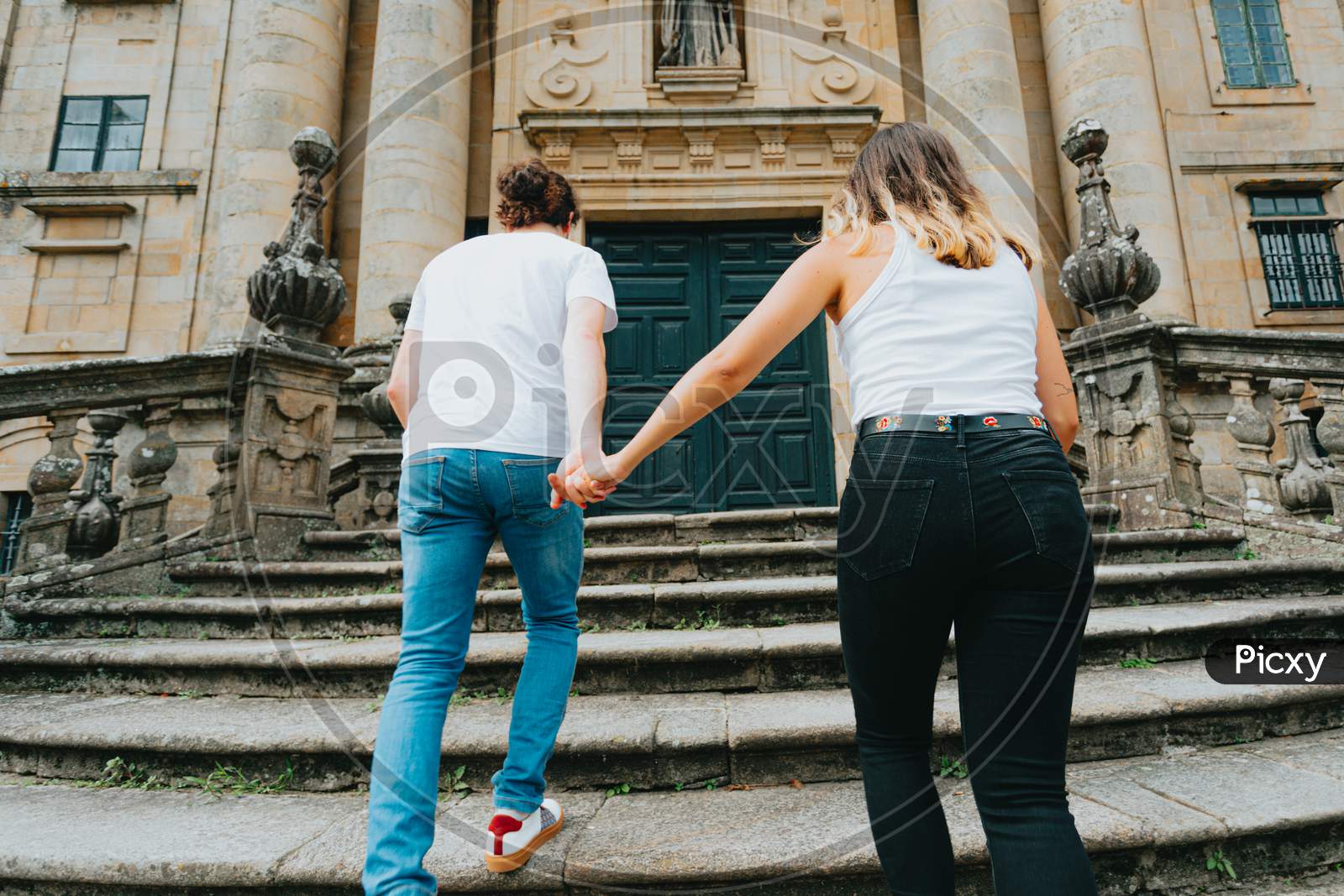 Young Couple Going Up Stairs While Grabbing Hands In An Ancient Building