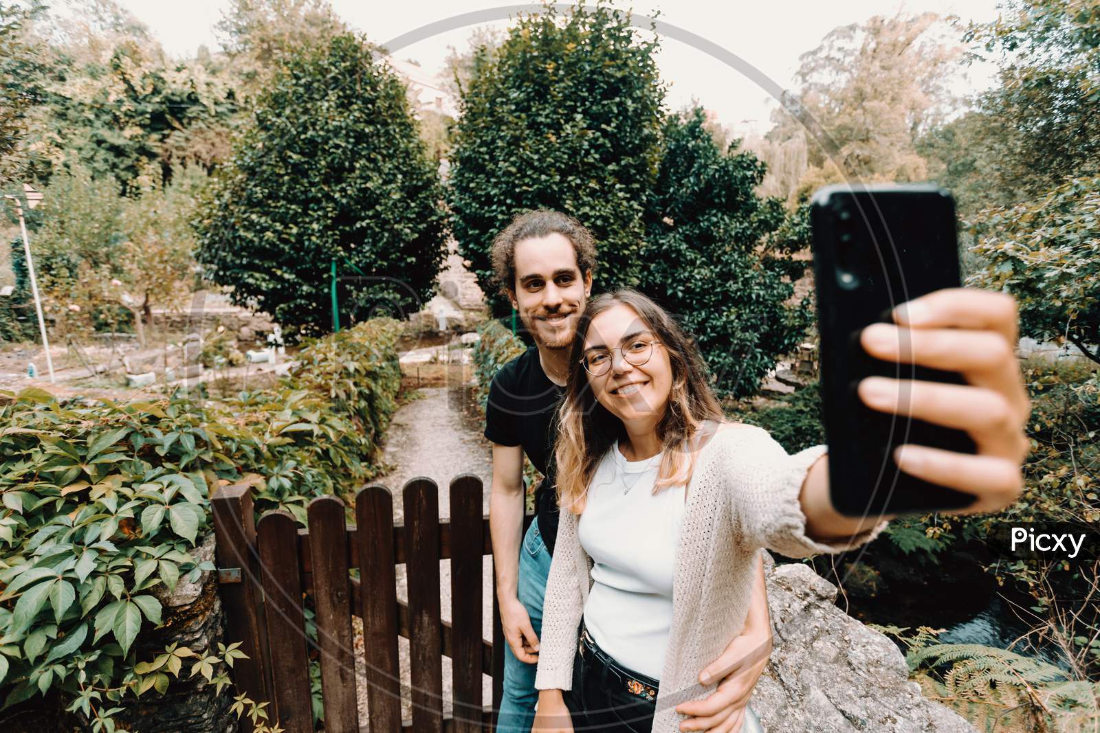 Young And Smiling Couple Taking A Selfie In Front Of A Beautiful Rural House