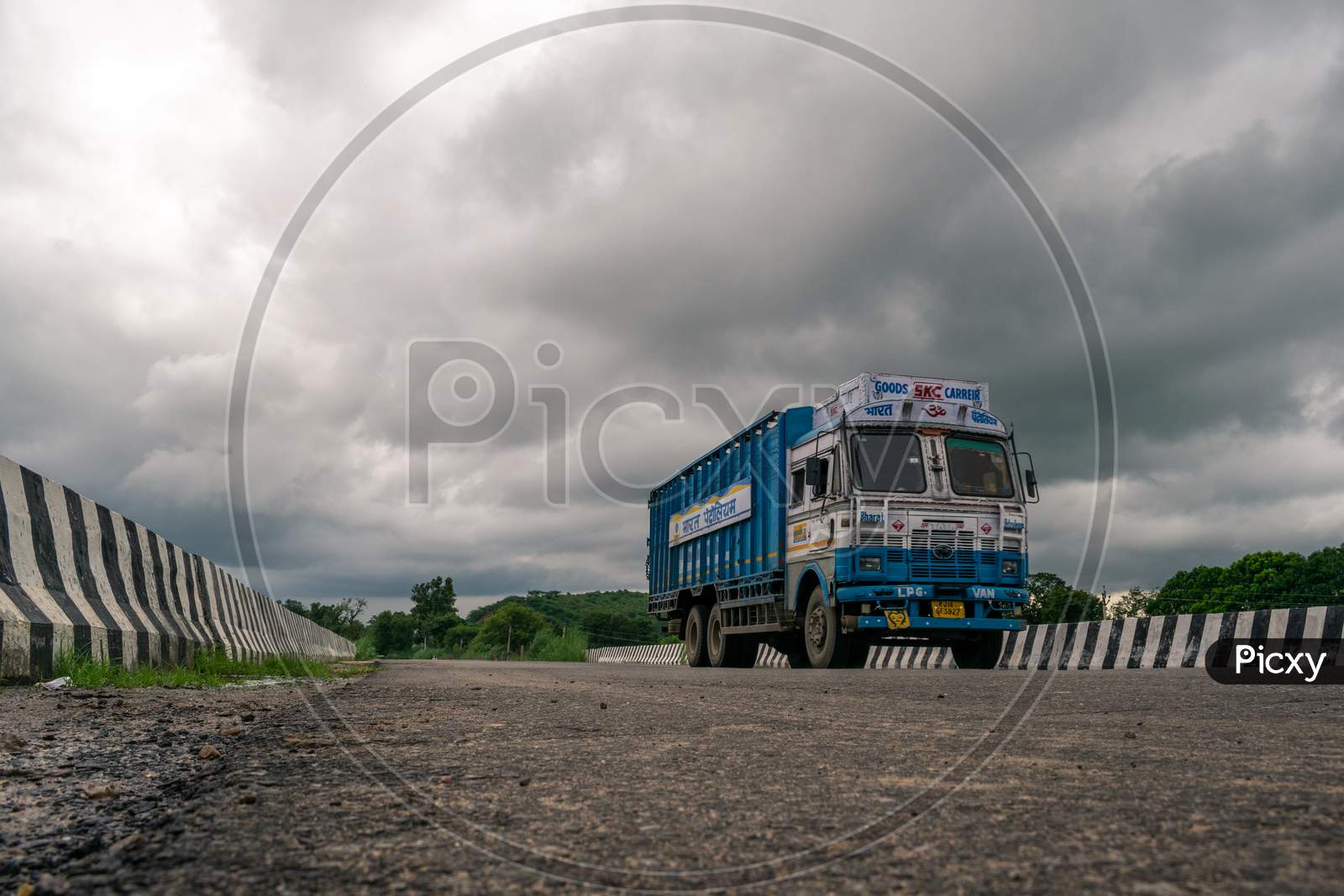 A Bharat Petroleum truck passing over a bridge under cloudy sky