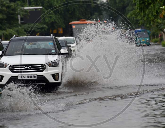 Commuters drive along a waterlogged road during heavy rain at Baba Kharak Singh Marg in New Delhi on August 28, 2020.