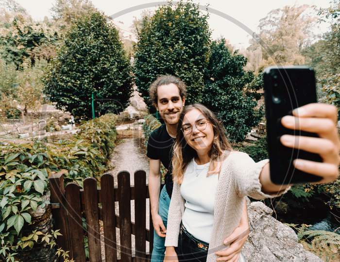 Young And Smiling Couple Taking A Selfie In Front Of A Beautiful Rural House