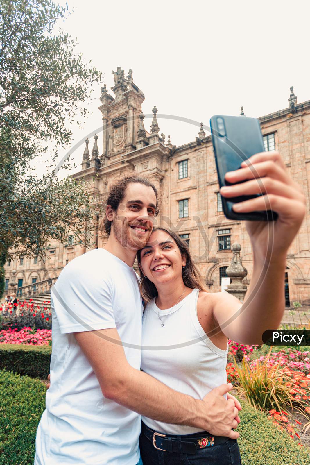 Vertical Shot Of A Young Couple Taking A Fancy Selfie In A Garden In Front Of An Old Building