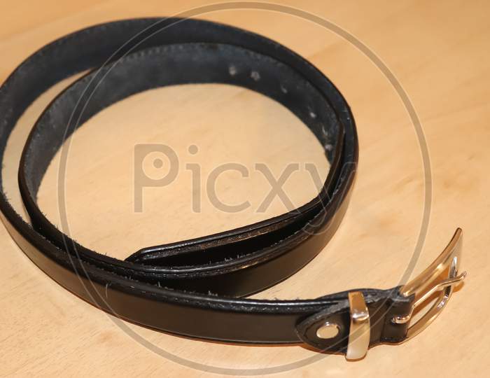 Slightly Old Black Leather Belt With A Metal Buckle On Old Wooden Background