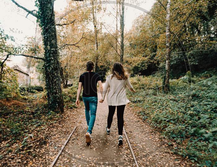 Young Couple Taking A Active Walk In The Park, View From Behind
