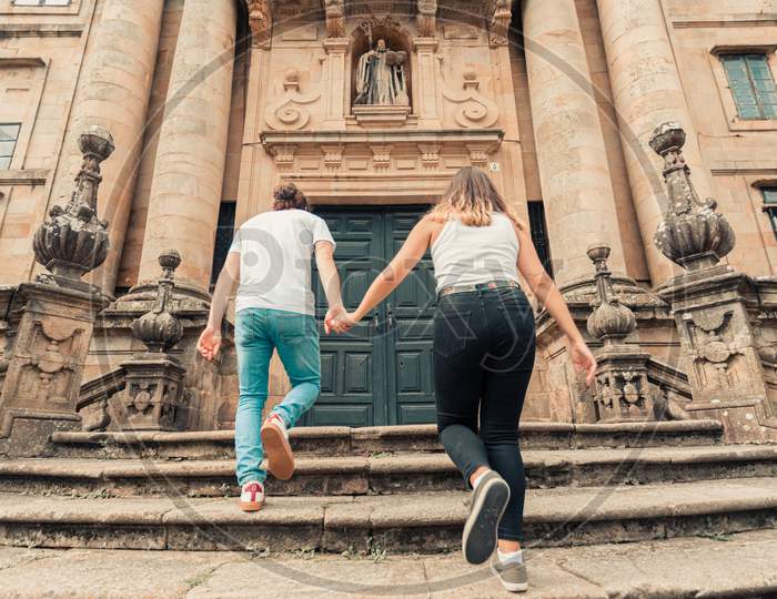 Young Couple Going Up Stairs In An Ancient Building