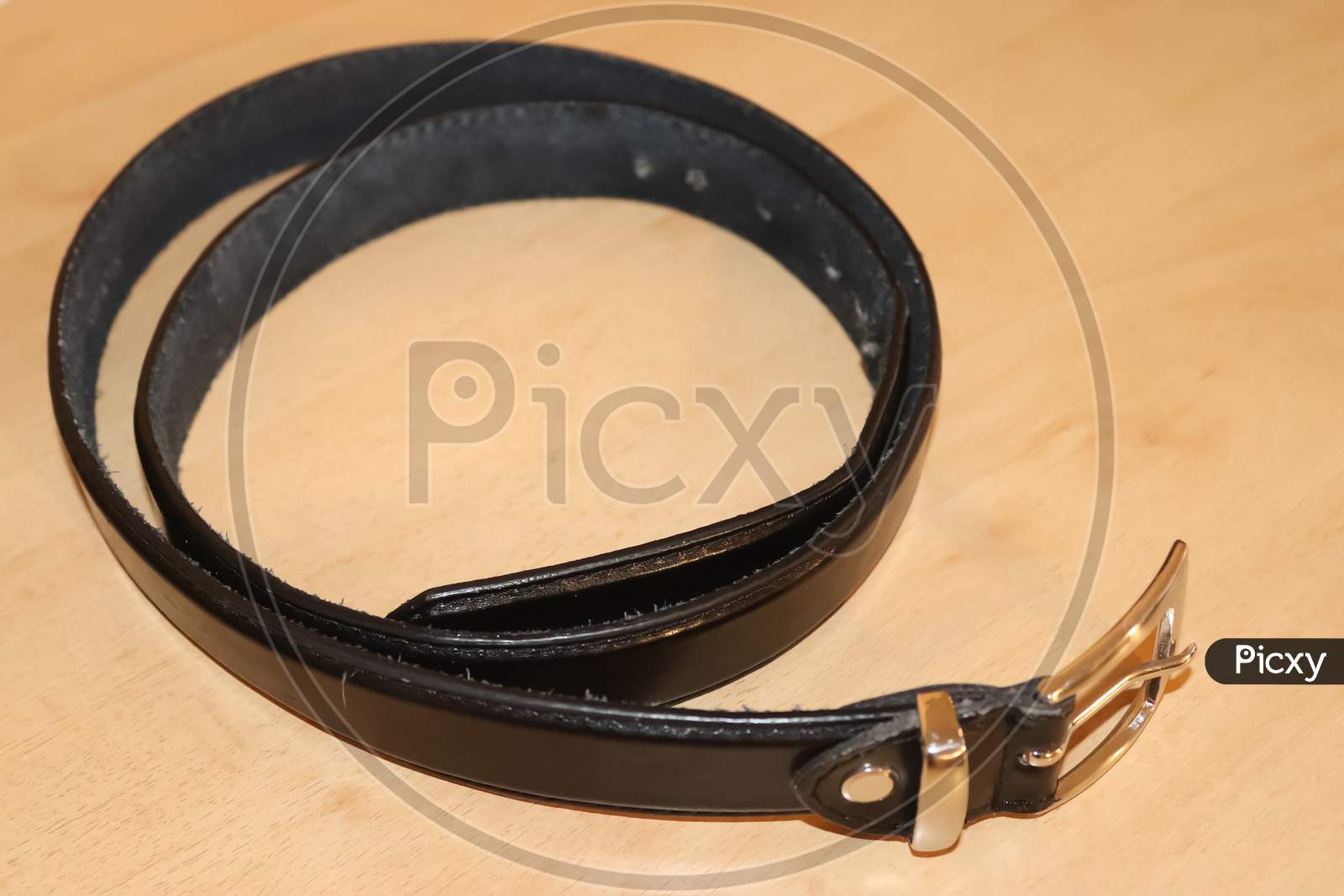 Slightly Old Black Leather Belt With A Metal Buckle On Old Wooden Background