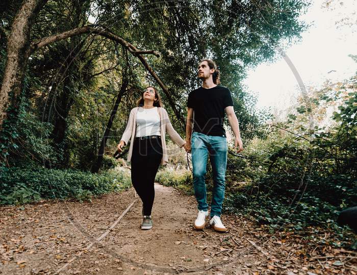 Front View Of A Young Couple Taking A Walk And Exploring The Forest During Autumn