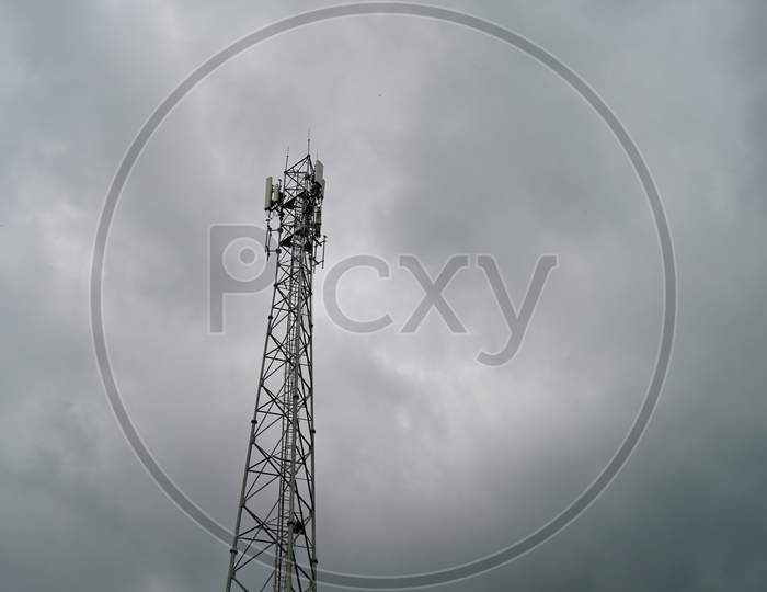 Information technology concept. Low angle view of Telecommunication tower with wet cloudy sky background. Modern wireless tower.