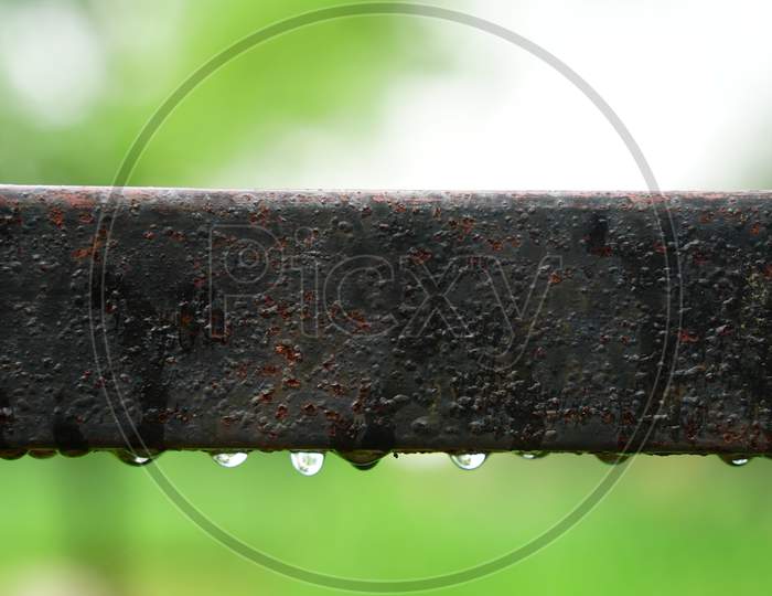 Rectangular iron pipe with iron drops, blurred background.