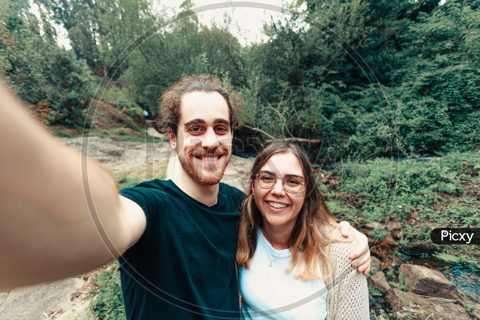 Young Couple Taking A Selfie In The Forest While Smiling