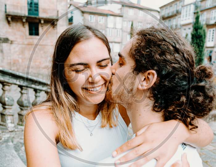 Young Man Kissing His Girlfriends While She Smiles