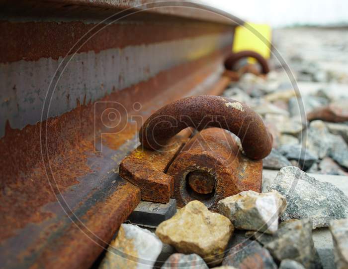 Selective focus on Pebbles and iron hook connected with railway sleeper. Scattering stones along with the track.