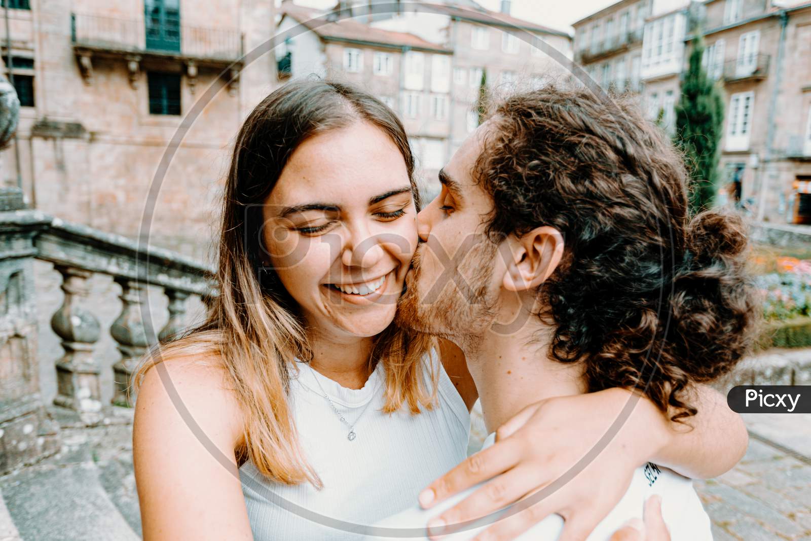 Young Man Kissing His Girlfriends While She Smiles