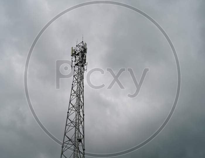Information technology concept. Low angle view of Telecommunication tower with wet cloudy sky background. Modern wireless tower.
