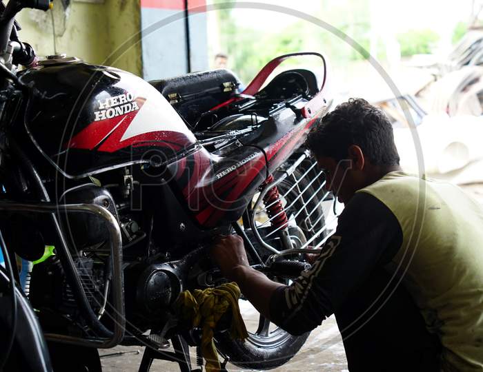 Professional Indian Mechanic repairing a bike in a workshop. Bike engineer opening combustible engine.