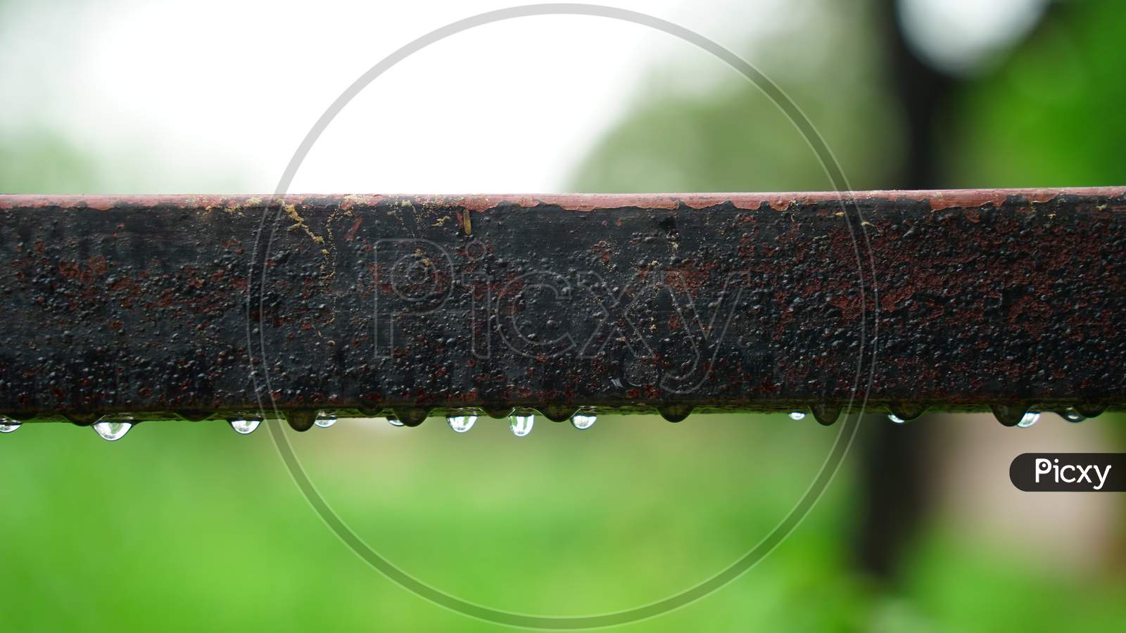 Selective focus on old rectangular iron pipe with rainy water drops. Rough old pipe with blurred background.
