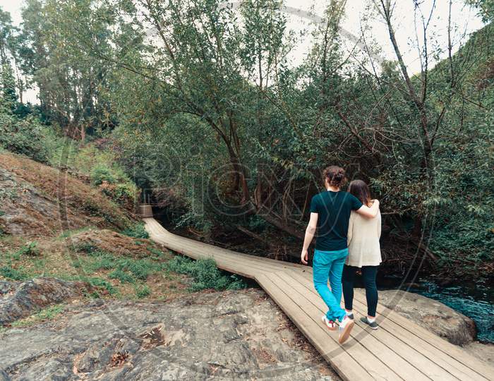 Young Couple Having A Walk By Near The River In The Forest