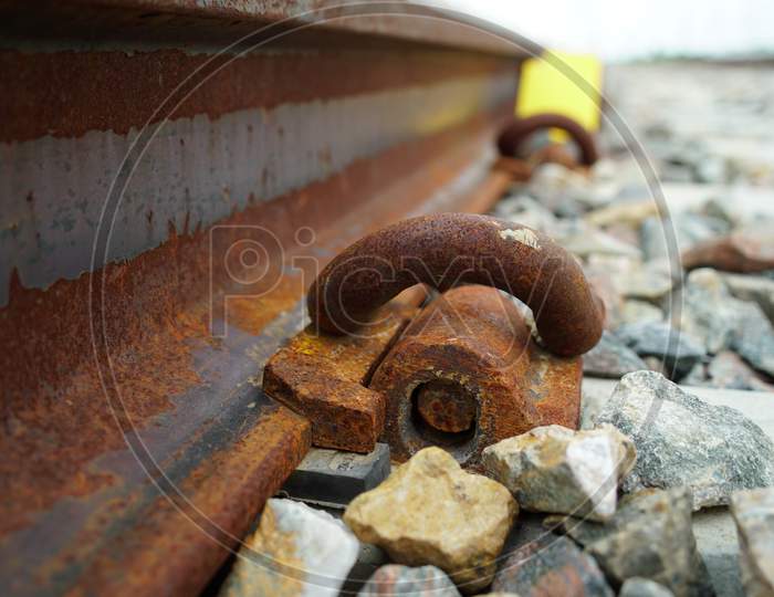 Selective focus on Pebbles and iron hook connected with railway sleeper. Scattering stones along with the track.