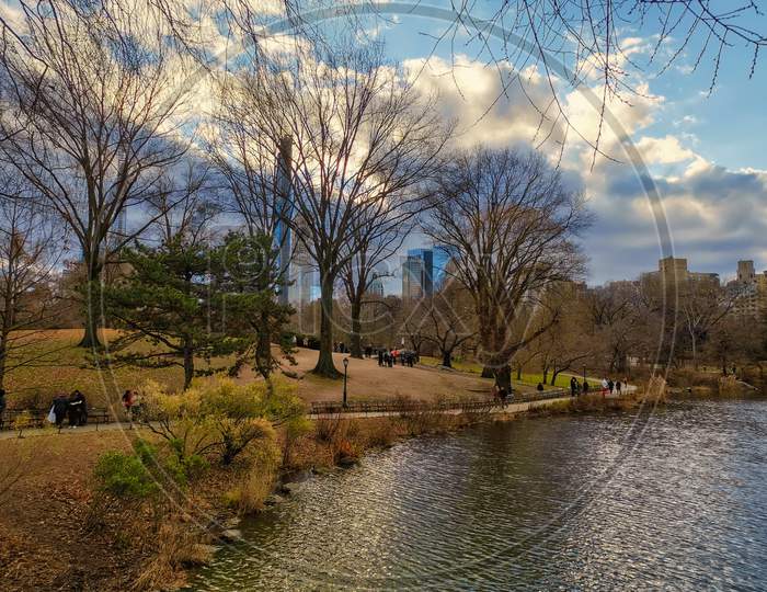 The central park, New York city daylight view with people walking, new York skyline ,reflection in water , clouds and trees