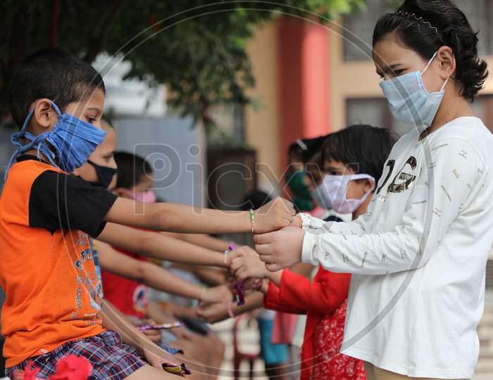 Girls tie rakhi on the wrists of boys at an orphanage on the occasion of Raksha Bandhan Festival in Jammu on August 3, 2020.