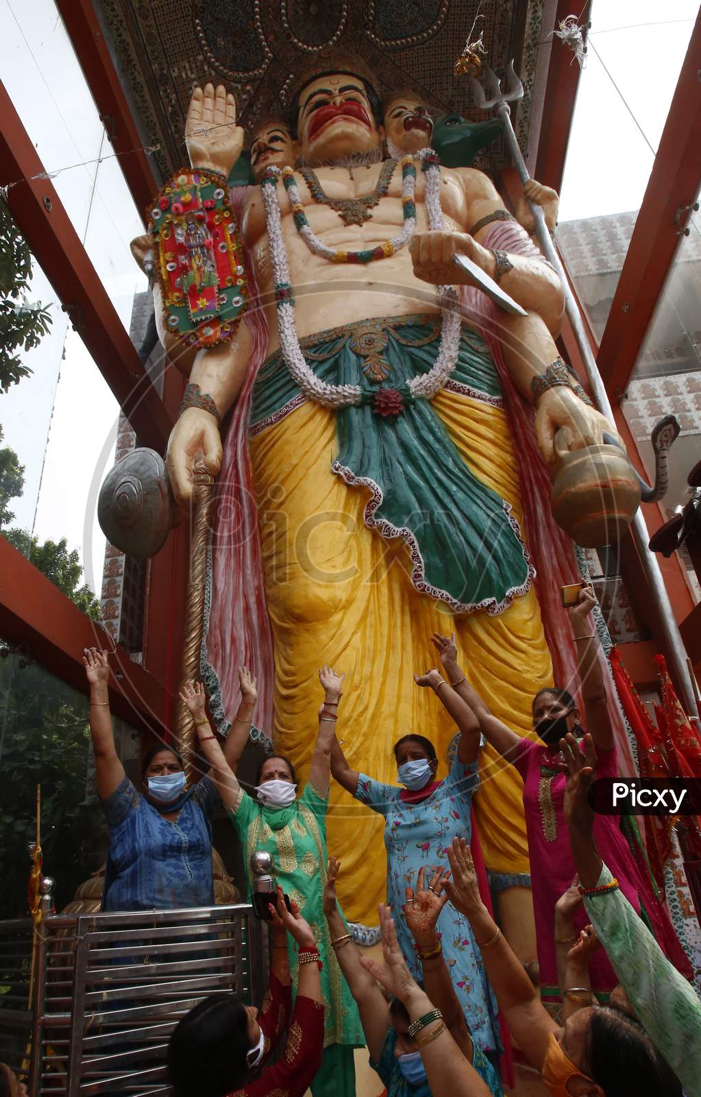 Devotees react after tying a 32-feet long Rakhi to an idol of Hindu lord Hanuman at the temple premises in Chandigarh, on August 3, 2020.