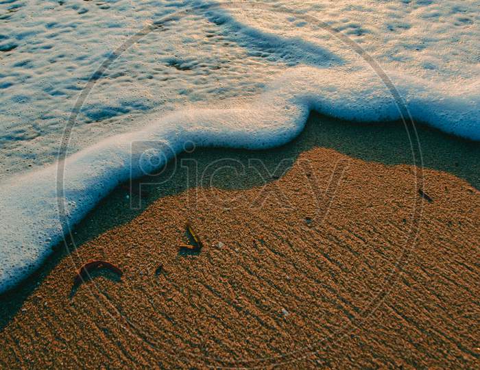 Minimalistic Tide With Lot Of Foam Over The Sand