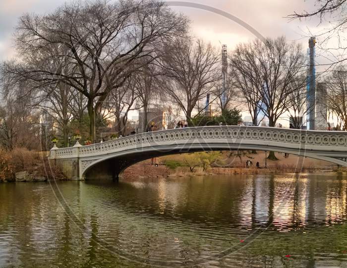 The bow bridge in central park, New York city daylight view with reflection in water , skylines,clouds and trees