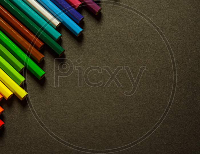 Tidy And Colorful Pencils On The Top Left Corner Over A Dark Background