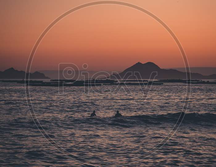 Two Surfers In The Sea In Front Of The Islands