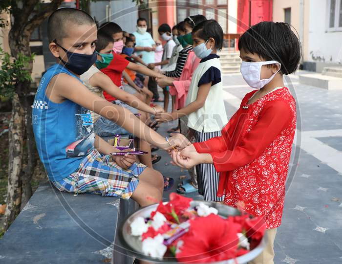 Girls tie rakhi on the wrists of boys at an orphanage on the occasion of Raksha Bandhan Festival in Jammu on August 3, 2020.