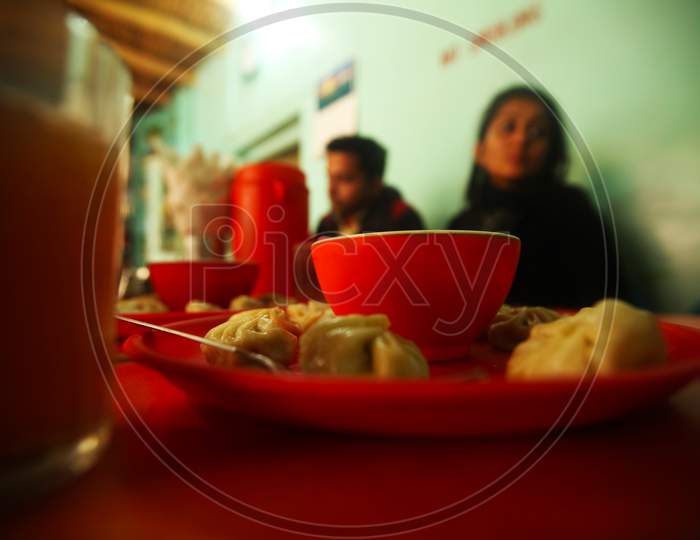 Close up shot of a Momos Plate with People in the Background