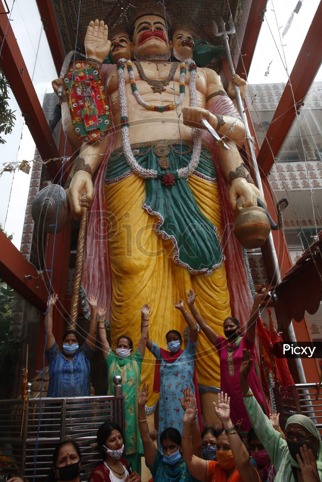 Devotees reacts after tying a Rakhi to 32 feet long idol of the Hindu lord Hanuman at the temple premises in Chandigarh, on August 3, 2020.