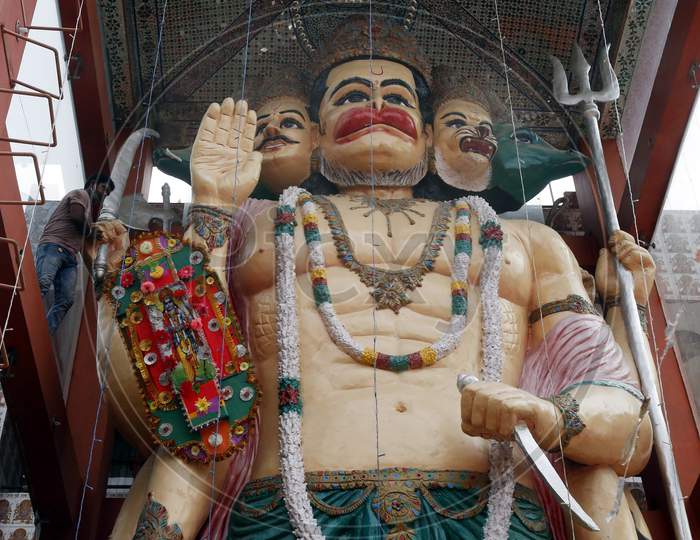 A devotee ties a 32-feet long Rakhi to an idol of Hindu lord Hanuman at the temple premises in Chandigarh, on August 3, 2020.