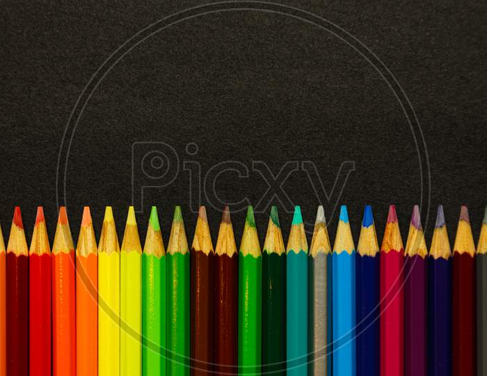 A Bunch Of Colorful Pencils Lined Up Over A Dark Background