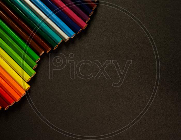 A Wave Made Of Colorful Pencils Over A Dark Background