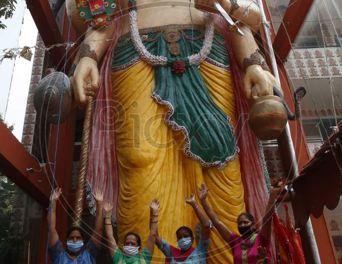 Devotees reacts after tying a Rakhi to 32 feet long idol of the Hindu lord Hanuman at the temple premises in Chandigarh, on August 3, 2020.