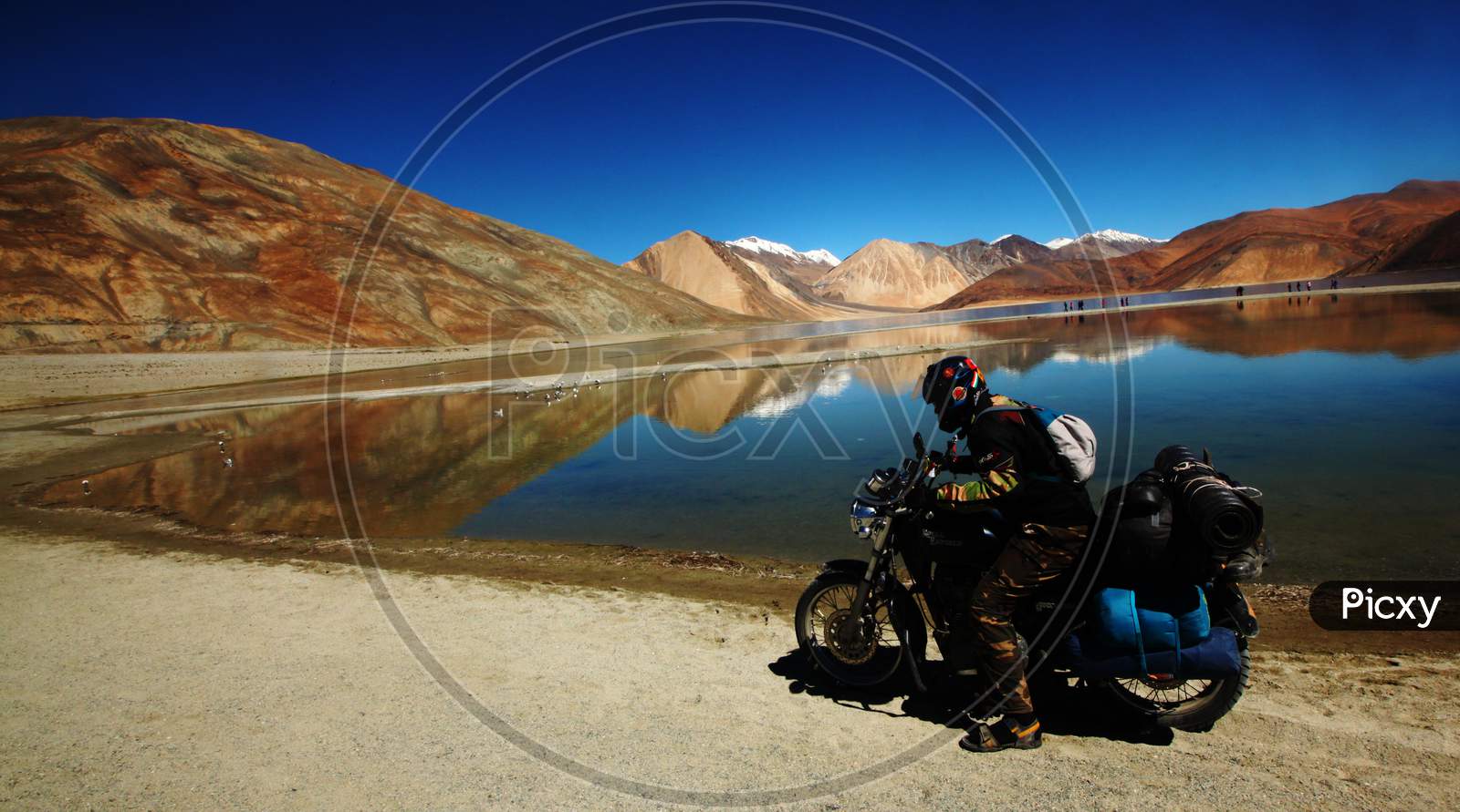 A Bike Rider in Leh with Snow Capped Mountains and Pangong Tso Lake in the Background