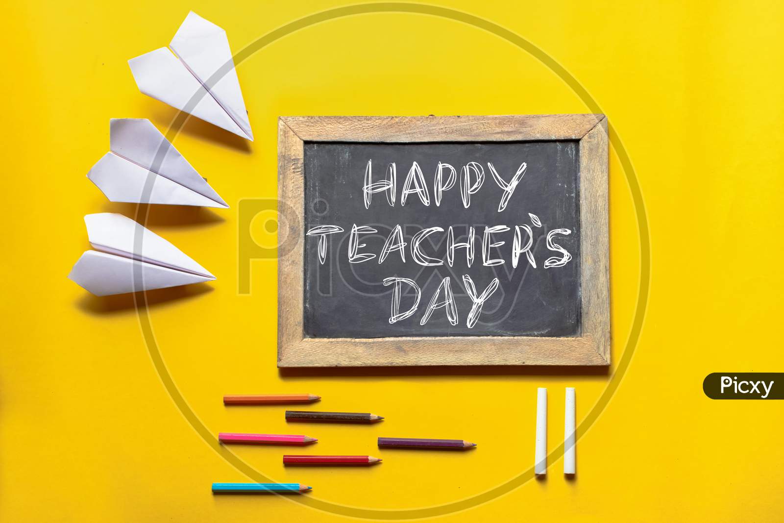 Happy Teacher's Day Conceptual Photo With Paper Plane, Slate Board, Color Pencils And Chalk